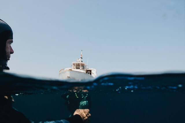 Over under shot of a man scuba diving near a boat
