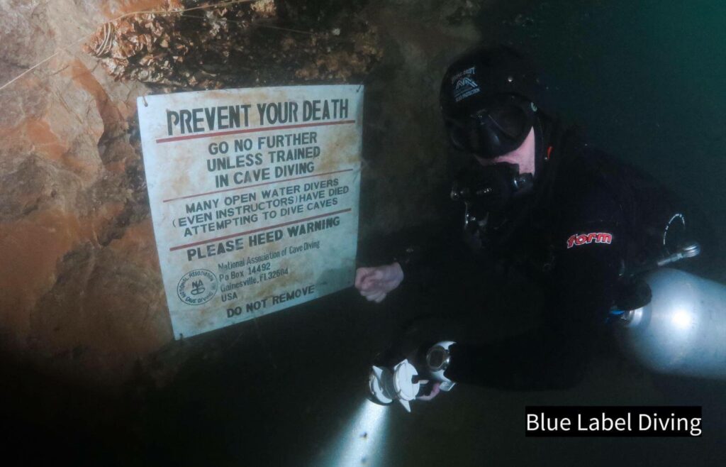 Cave Photo Credit: Claus Rasmussen, Blue Label Diving (Phuket, Thailand) A cave diver sims next to a sign warning of death if entering the cave system without a guide