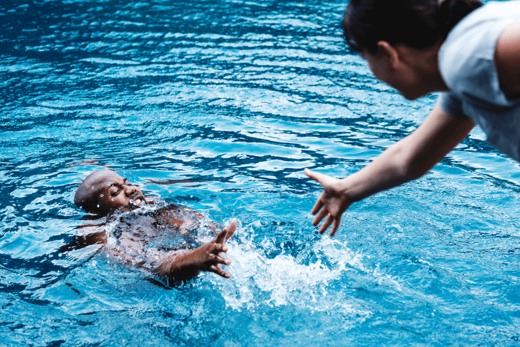 Man overboard procedure in action as a man stretches his hand out to someone struggling in the water Man overboard procedure in action as a man stretches his hand out to someone struggling in the water