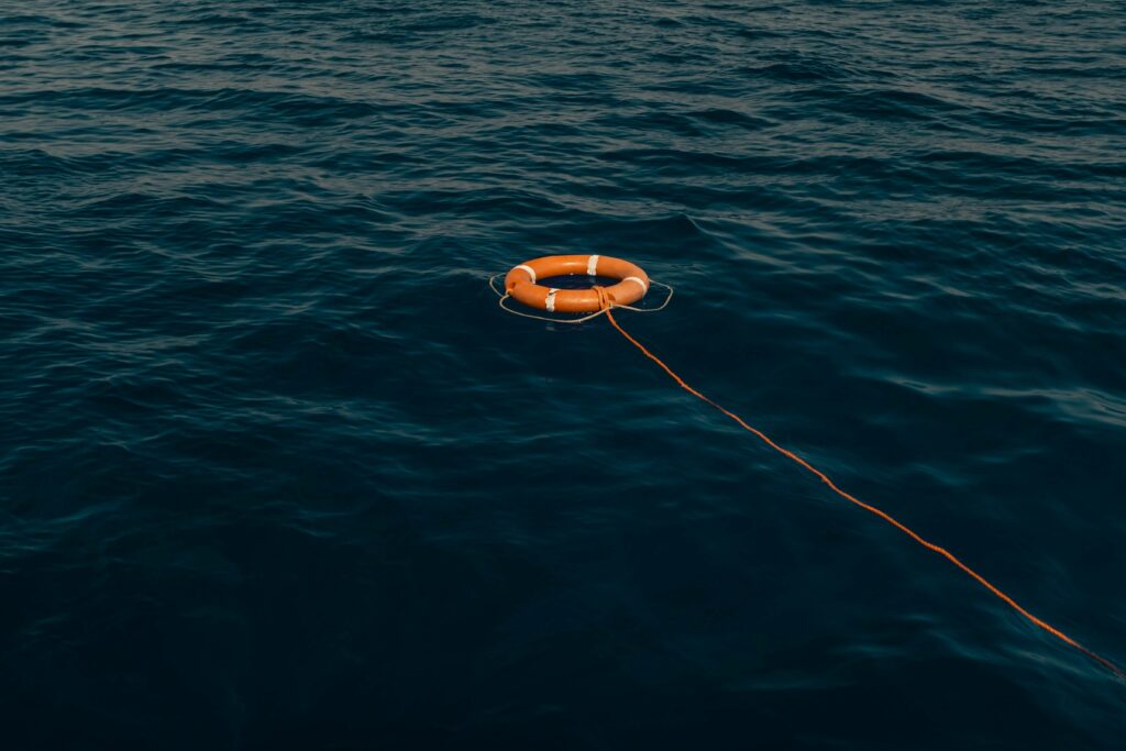Orange life buoy on a rope in the ocean Orange life buoy on a rope in the ocean