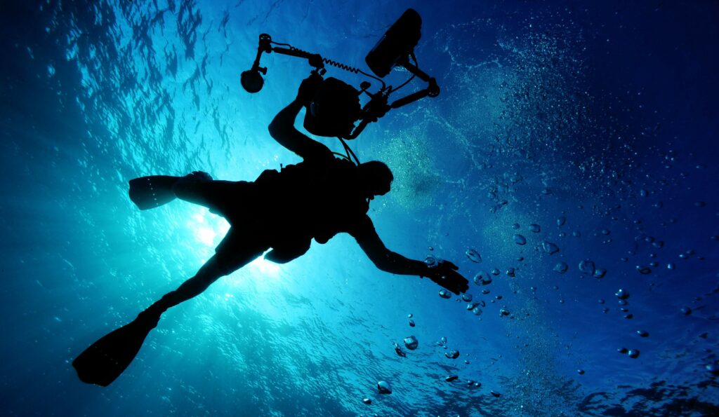 Silhouette of scuba diver with photography equipment Silhouette of scuba diver with photography equipment