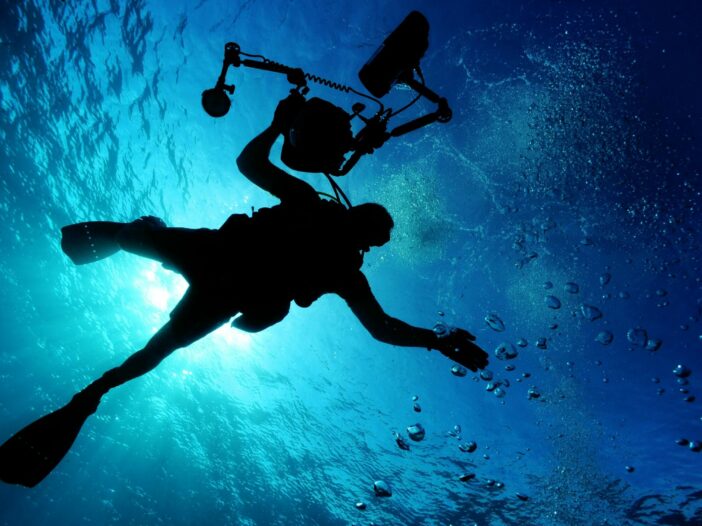 Silhouette of scuba diver with photography equipment