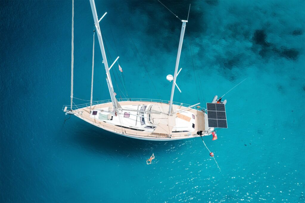 Aerial view of a sailboat and woman swimming next to it Aerial view of a sailboat and woman swimming next to it
