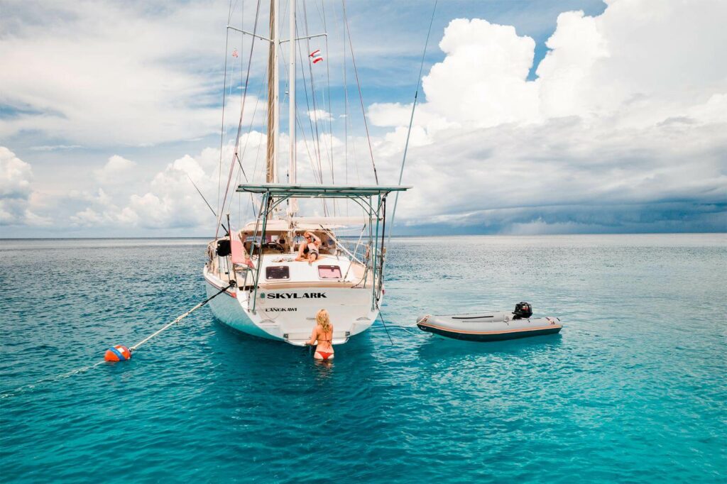 Sailboat on a mooring line next to a dinghy in Thailand Sailboat on a mooring line next to a dinghy in Thailand