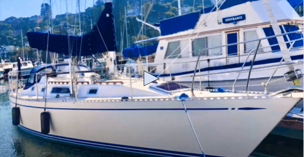 White Nordic 40 sailboat with blue sails in a marina