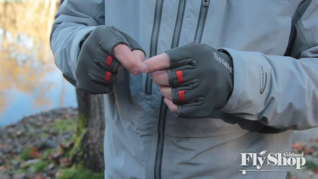 Person wearing Simms fingerless gloves tying a fishing line Person wearing Simms fingerless gloves tying a fishing line