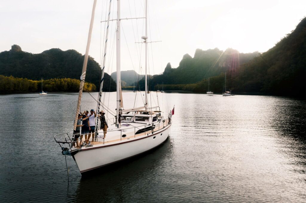 Friends standing at the bow of a sailboat in Thailand Friends standing at the bow of a sailboat in Thailand