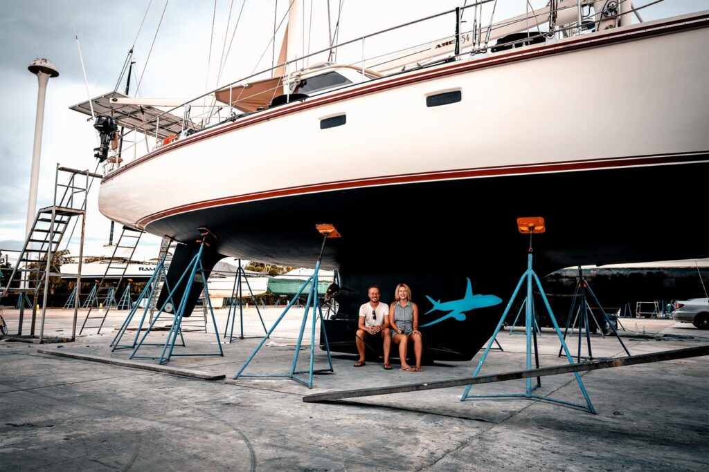 Couple sit in front of their sailboat during an overhaul Couple sit in front of their sailboat during an overhaul