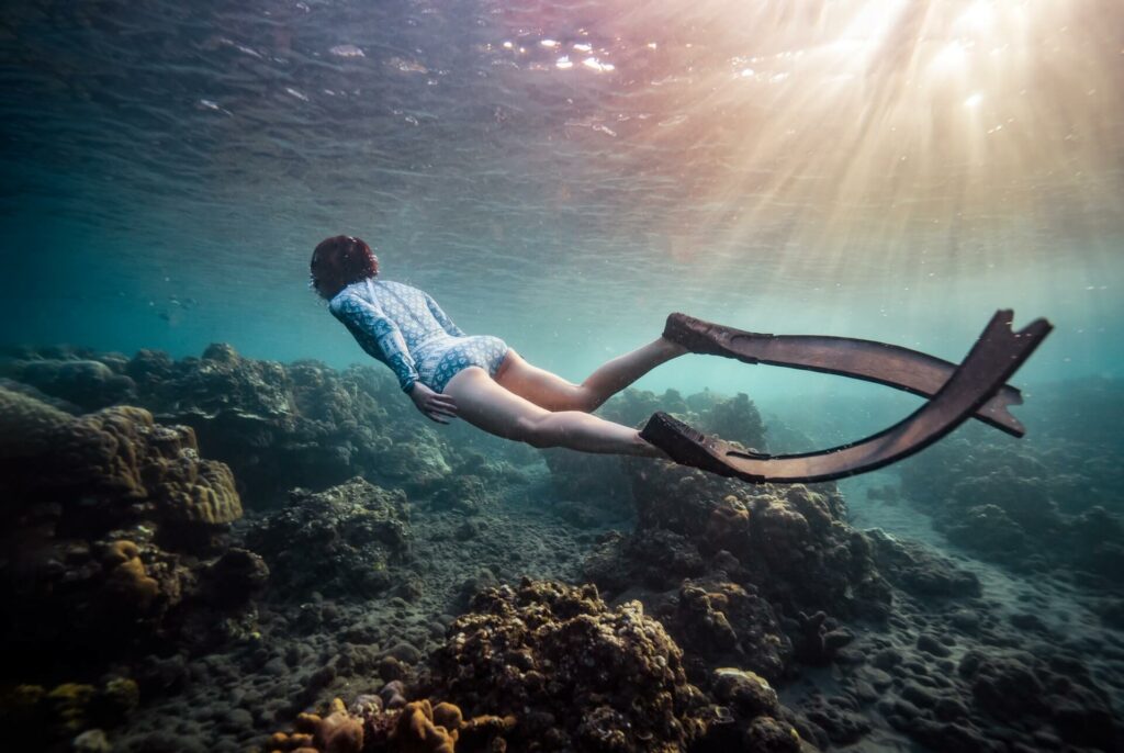 Woman swimming with freediving fins over a coral reef Woman swimming with freediving fins over a coral reef