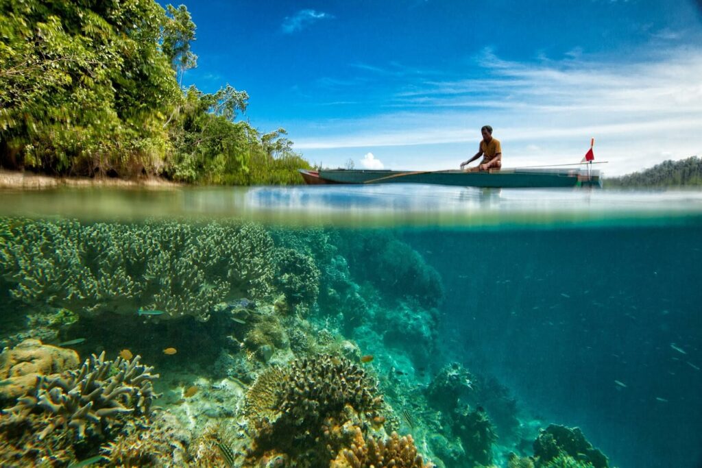 Man fishing over a coral reef in a canoe Man fishing over a coral reef in a canoe
