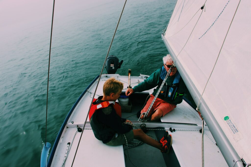 A man and his son on a sailboat wearing lifejackets A man and his son on a sailboat wearing lifejackets