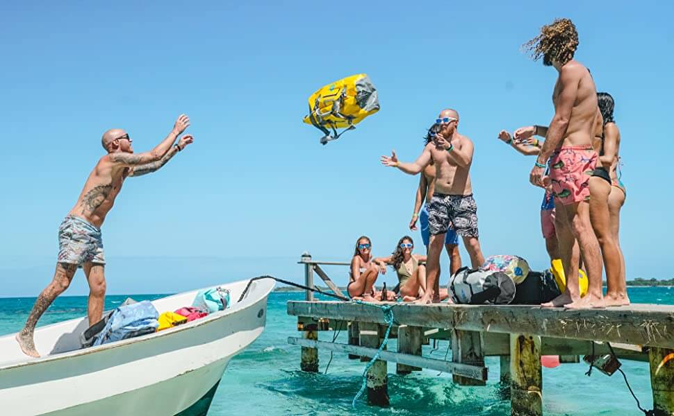 Enter code #BOATLIFE during checkout at SkogAKust.com to receive 10% off of your entire order. Man throws a yellow Skog A Kust Duffel bag from a boat