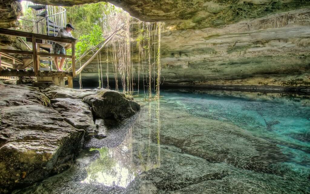 Bahamas National Parks A man stands over a pool of water inside of a cave at Inagua National park in the Bahamas