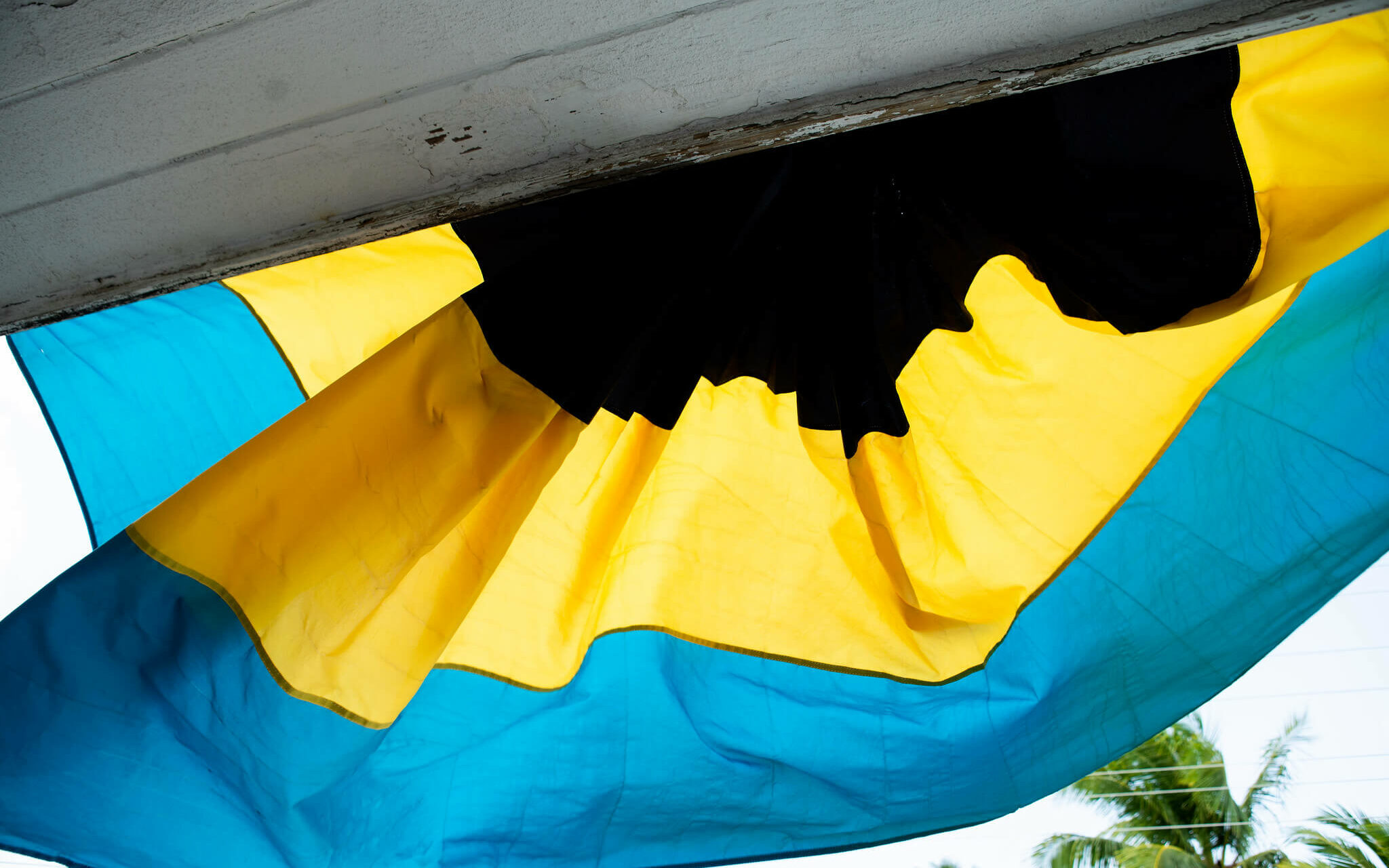 The Bahamas Flag The Bahamas country flag hanging from a front porch in front of palm trees