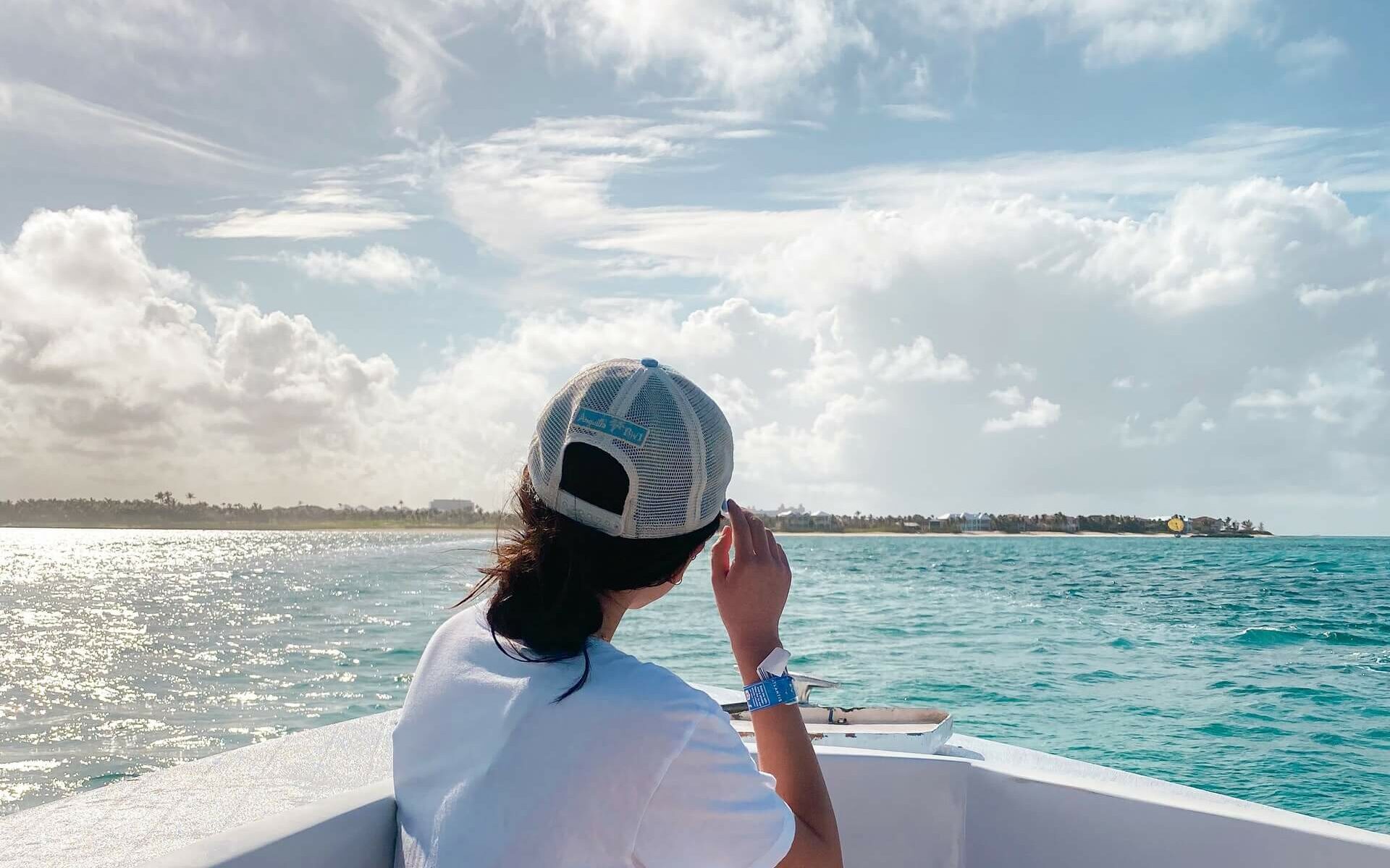 View of the Bahamas from a boat A woman in a hat looking at an island from a boat in the Bahamas