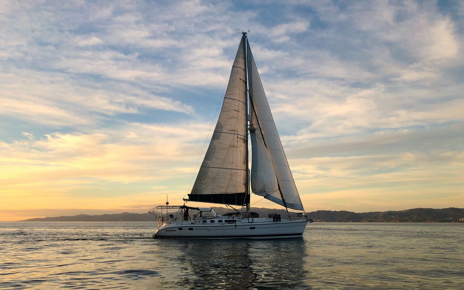 A sailboat sits on the horizon while sailing around the world A sailboat sits on the horizon while sailing around the world
