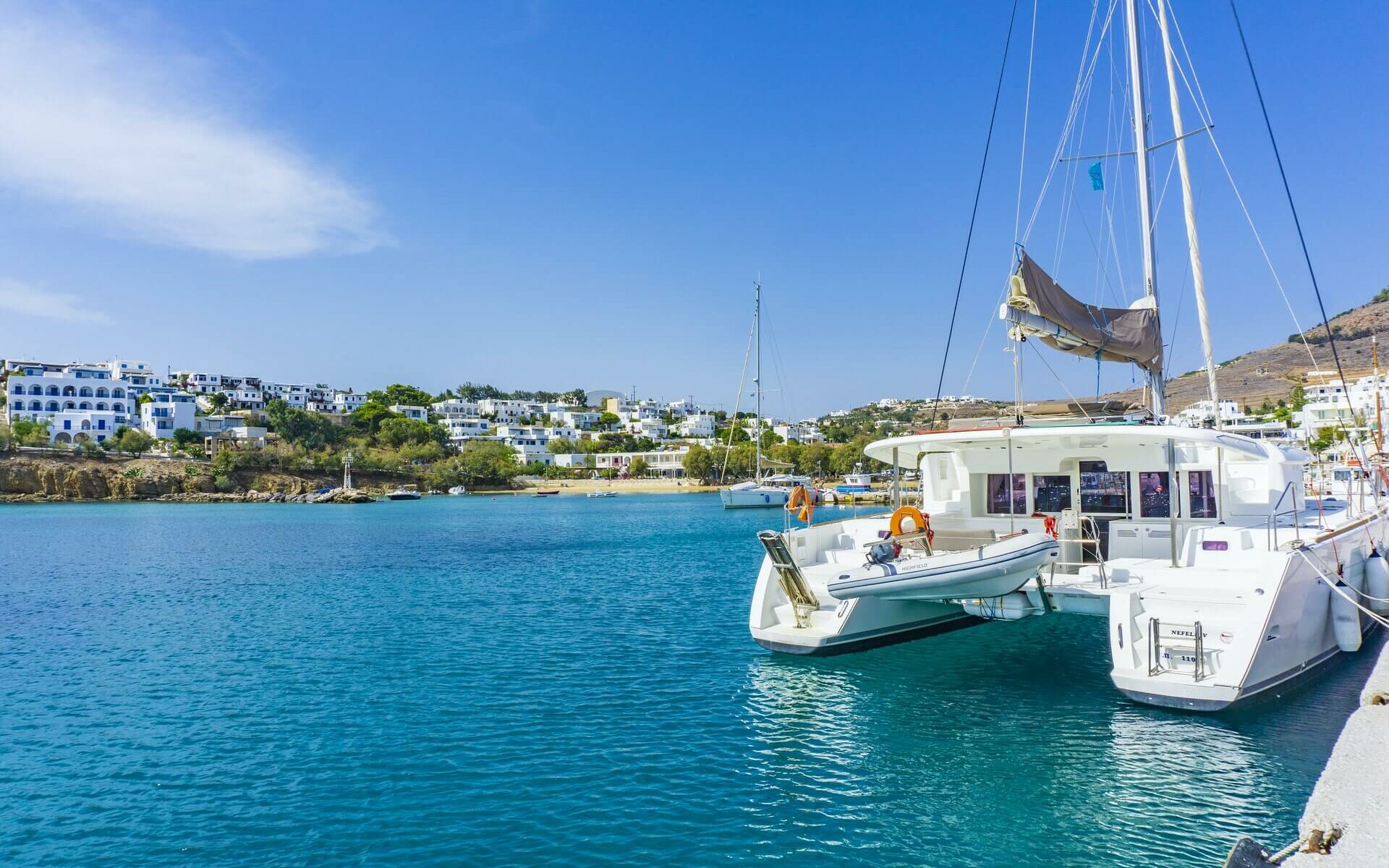 a white catamaran docked near shore in blue water a white catamaran docked near shore in blue water