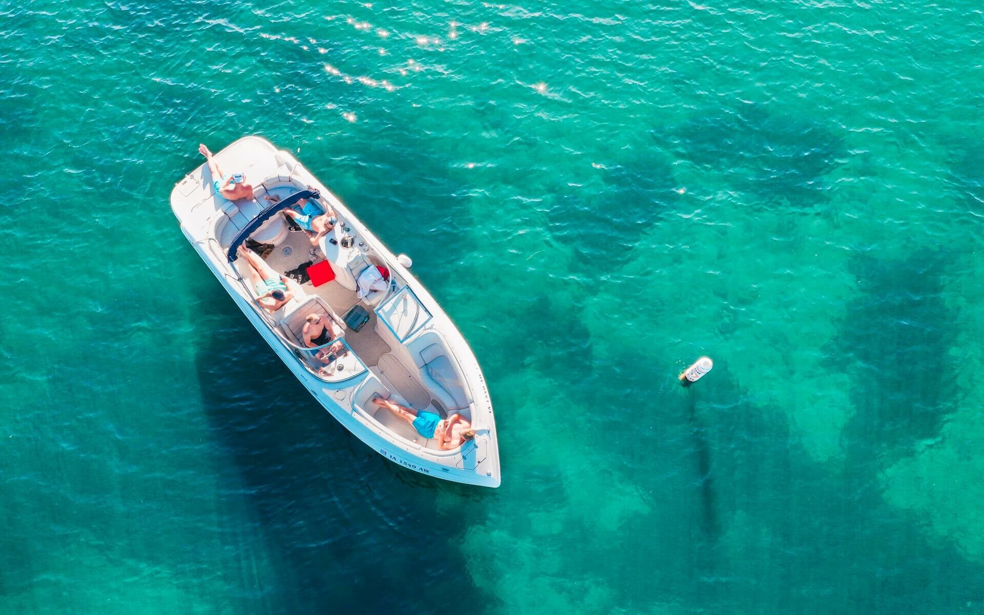 People lounging on a boat in the sun on clear, turquoise blue water People lounging on a boat in the sun on clear, turquoise blue water
