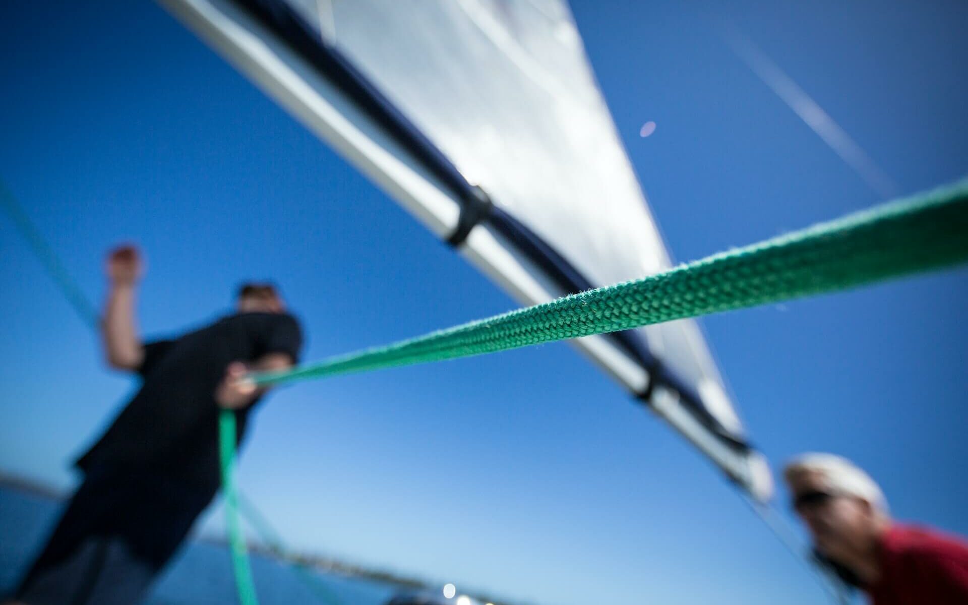 a man helps adjust the sails on a sailboat a man helps adjust the sails on a sailboat
