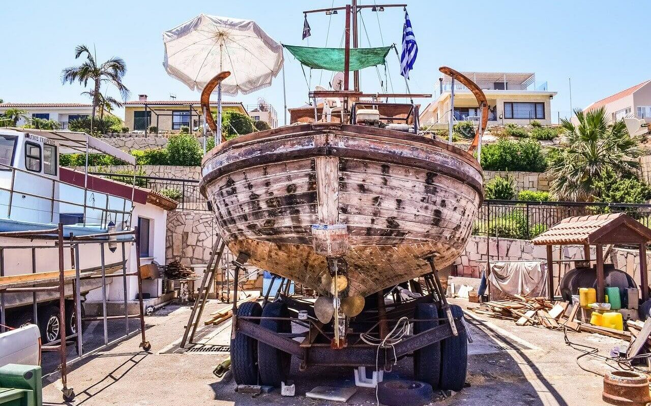 An old wooden boat on a trailer being prepared for maintenance and repairs, which is a big cost of boat ownership An old wooden boat on a trailer being prepared for maintenance and repairs, which is a big cost of boat ownership